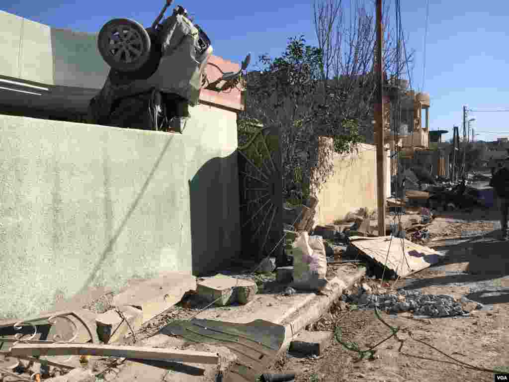 A burnt car, catapulted by an explosion onto a house, is seen perched on the building’s wall, in Mosul, Iraq, Jan. 12, 2017. (K. Omar/VOA Kurdish)