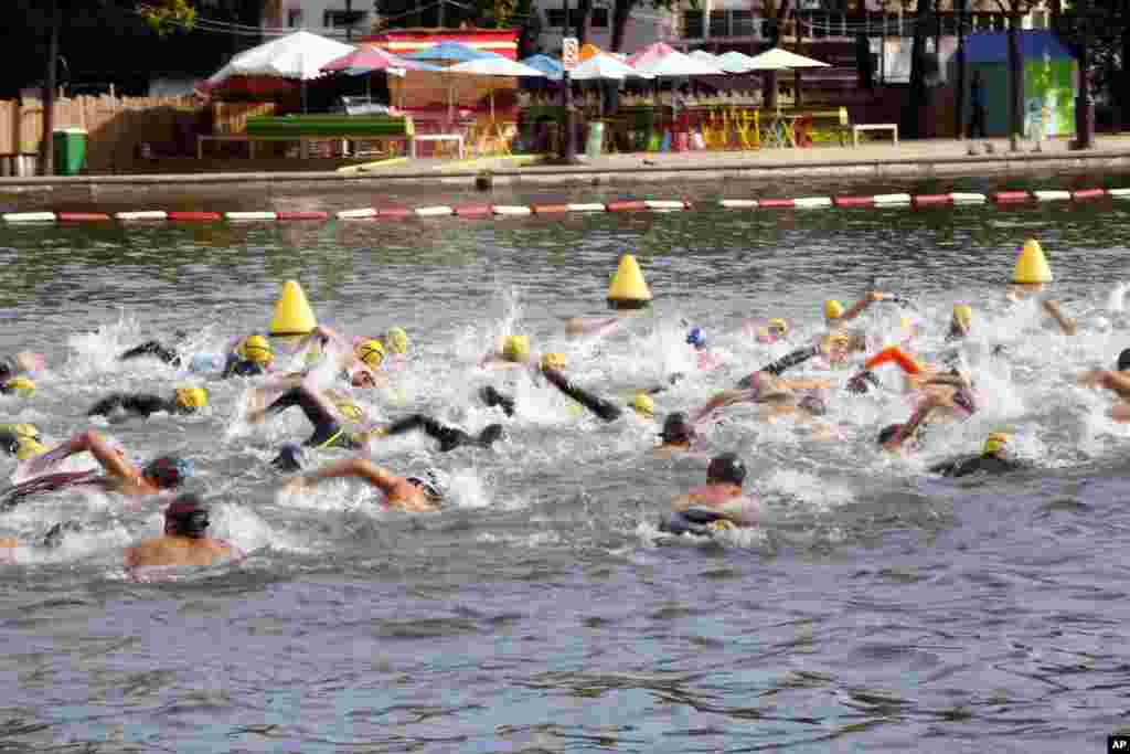 Swimmers compete in a race organized by the Paris Swim association, in the La Villette basin, Paris, France.