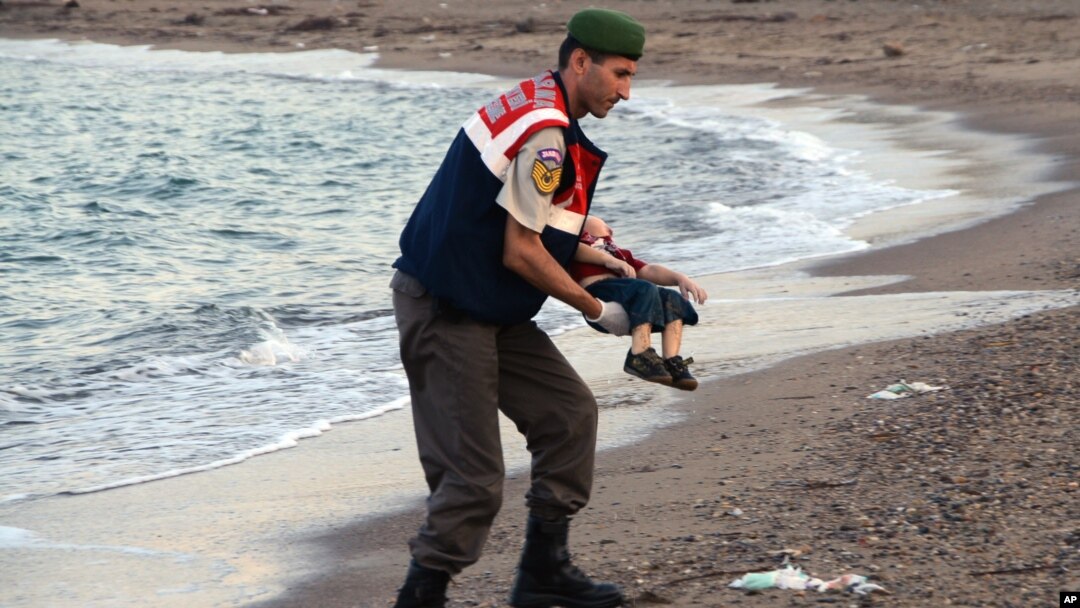 A paramilitary police officer carries the lifeless body of an unidentified migrant child, lifting it from the seashore near the Turkish resort of Bodrum, Sept. 2, 2015.