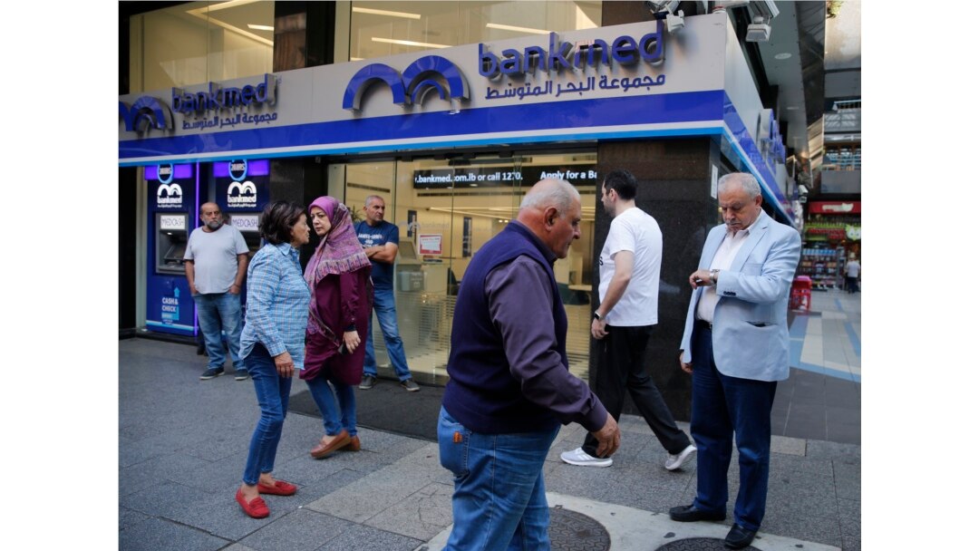 Clients wait outside a bank for its re-opening after a two-week closure, in Beirut, Lebanon, Nov. 1, 2019.