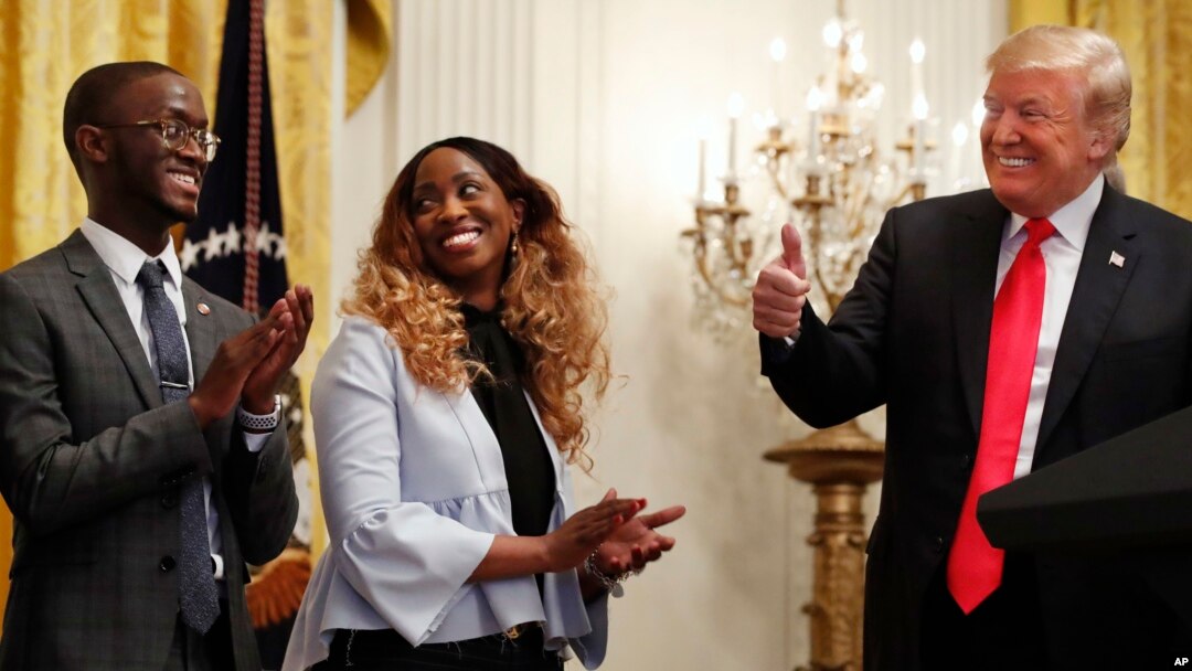 President Donald Trump, right, gives the thumbs up to Cam'eron Hill, left, and his mother LaSonya Hill, of Jacksonville, Fla., during an event about taxes, June 29, 2018, in the East Room of the White House in Washington.