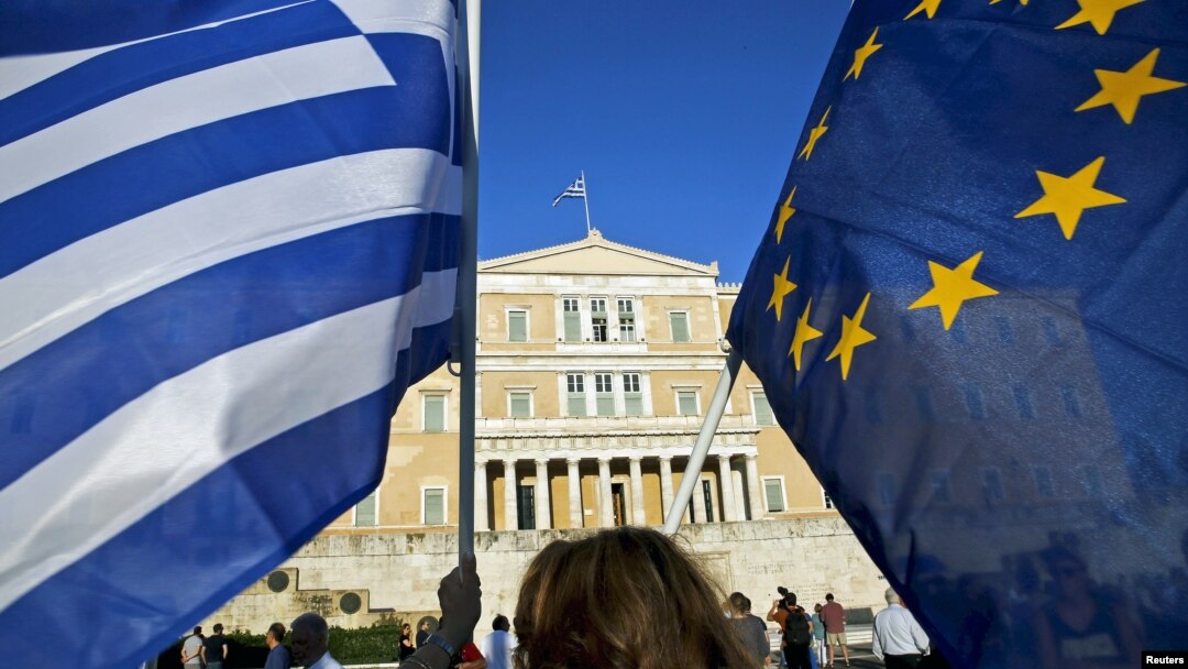 A woman waves a Greek national flag and a European Union flag during a rally outside the Parliament, calling on the government to clinch a deal with its international creditors and secure Greece's future in the Eurozone, in Athens, Greece, June 18, 2015.