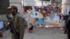 FILE - A soldier stands near a woman reading messages left by people for the victims of the Taliban attack on a school, in Peshawar, Pakistan, Dec. 23, 2014. 
