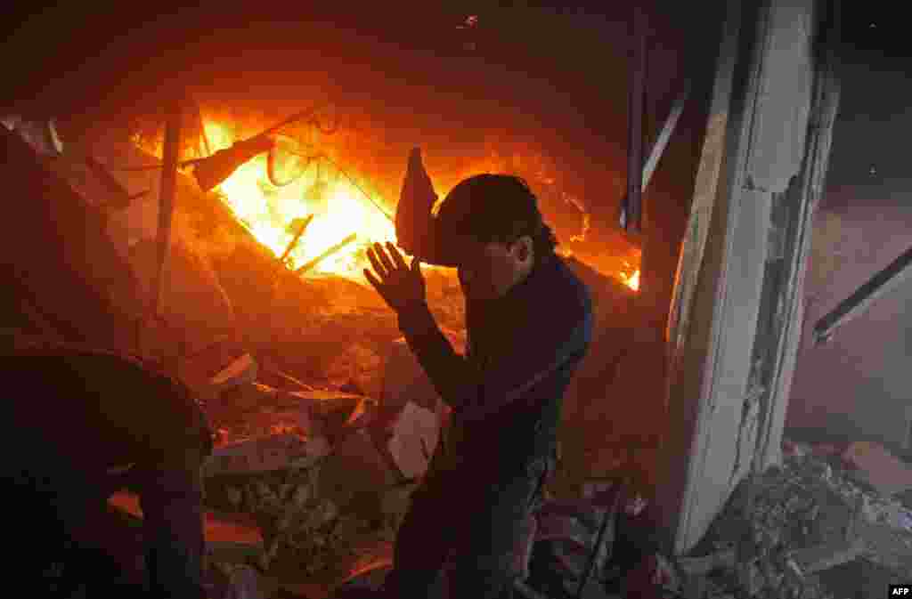 A Syrian man searches for people in a fire following regime airstrikes on the rebel-held besieged town of Douma in the eastern Ghouta region, on the outskirts of the capital Damascus.
