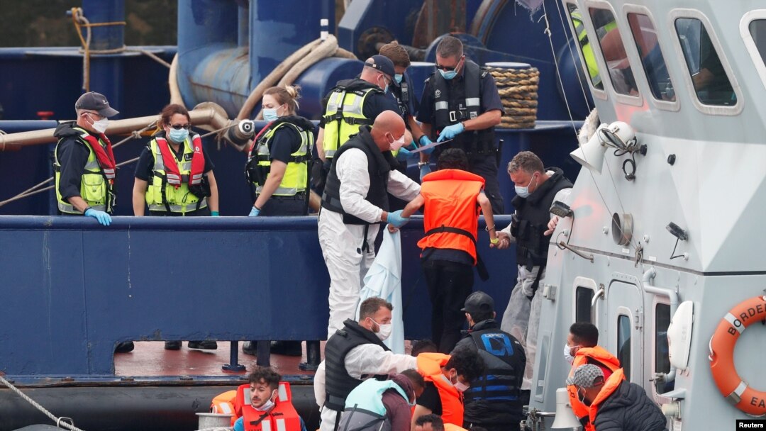 FILE - Migrants disembark after arriving at Dover harbor, in Dover, Britain, Aug. 12, 2020.