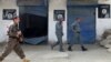 FILE - Afghan police walk past Islamic State militant flags on a wall, after an operation in the Kot district of Jalalabad province east of Kabul, Afghanistan, Aug. 1, 2016.
