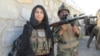 An Afghan National Army soldier and VOA reporter Ayesha Tanzeem, left, wait at a police checkpoint barrier in Achin, a district in eastern Afghanistan.
