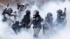 Police in riot gear move through a cloud of smoke as they detain a protester at the Hong Kong Polytechnic University.