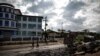 FILE - An abandoned market in Cameroon's majority anglophone South West province in Buea, is seen Oct. 3, 2018, next the wreckage of a car allegedly burned by separatists fighters.