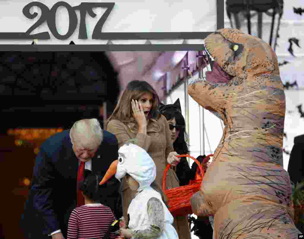 President Donald Trump and First Lady Melania Trump hand out treats as they welcome children from the Washington area and children of military families to trick-or-treat celebrating Halloween at the White House, Washington, Oct. 30, 2017.