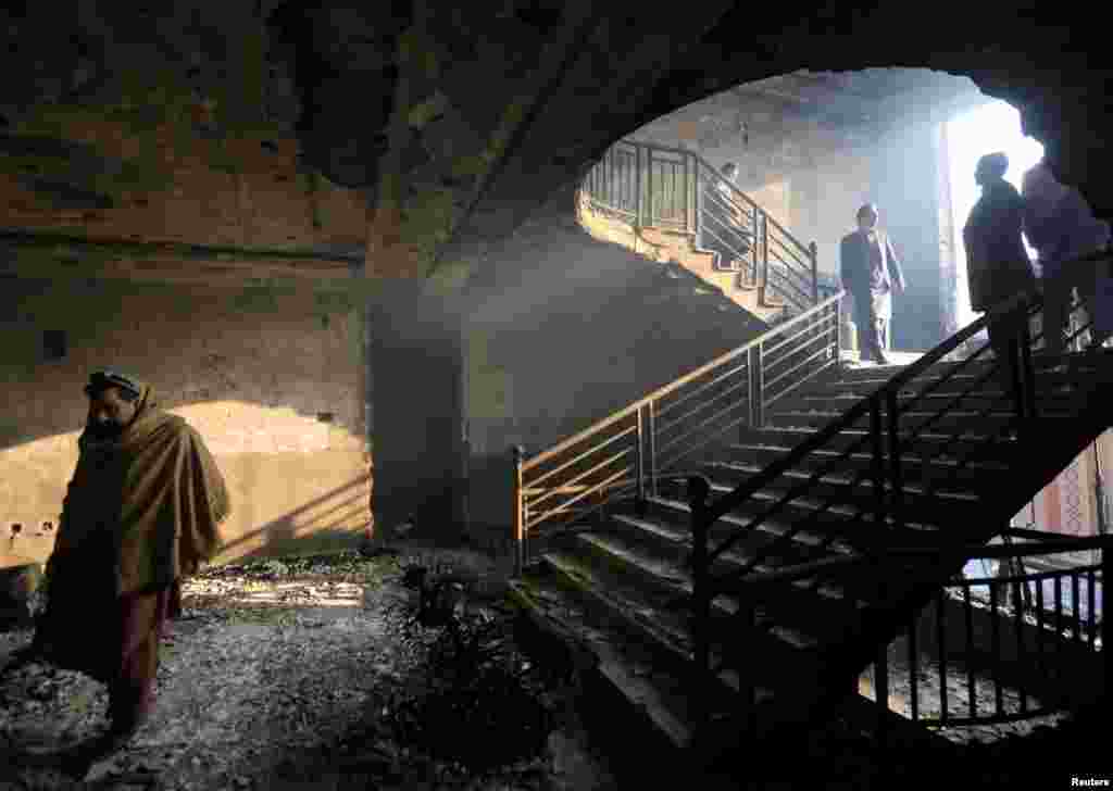 Afghan men inspect a burnt and damaged building at the site of yesterday's blast and gunfire in Jalalabad, Afghanistan.