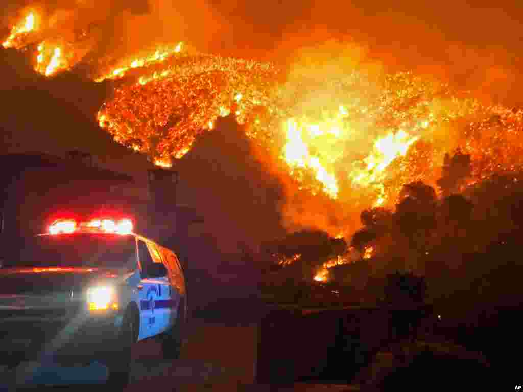In this photo provided by the Santa Barbara County Fire Department, wildfires burn canyons and ridges above Bella Vista Drive near Romero Canyon as the fight to contain the wildfires continues in Montecito, California, Dec. 12, 2017.