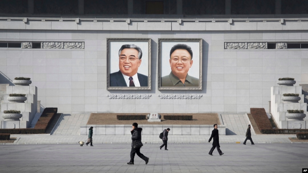 FILE - People walk past portraits of the late North Korean leaders Kim Il Sung and Kim Jong Il at Kim Il Sung Square in Pyongyang, North Korea.