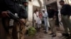 Police stand guard as a polio worker waits to give polio vaccine drops to children at a street in Peshawar, the capital of Khyber-Pakhtunkhwa province, Pakistan, March 30, 2014.