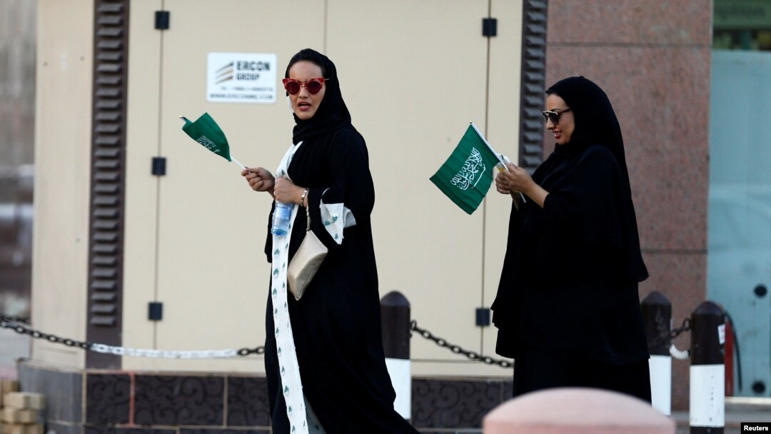Saudi women hold national flags as they walk on a street during Saudi National Day in Riyadh, Saudi Arabia, Sept. 23, 2016. 