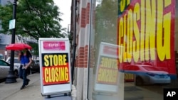 FILE - A passerby walks past a business storefront with store closing signs in Boston. U.S. unemployment benefit claims jumped sharply in the first week of December 2020.