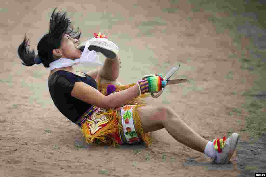 A &quot;scissors&quot; dancer grabs her shoe with her mouth while performing in a national scissors dance competition in the outskirts of Lima, Peru, Dec. 1, 2013.