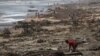 FILE - A boy sifts through debris on the beach, in the aftermath of Cyclone Batsirai, in the town of Mananjary, Madagascar, Feb. 8, 2022.