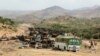 FILE - Villagers return from a market to Yechila town in south central Tigray walking past scores of burned vehicles, in Tigray, Ethiopia, July 10, 2021. 