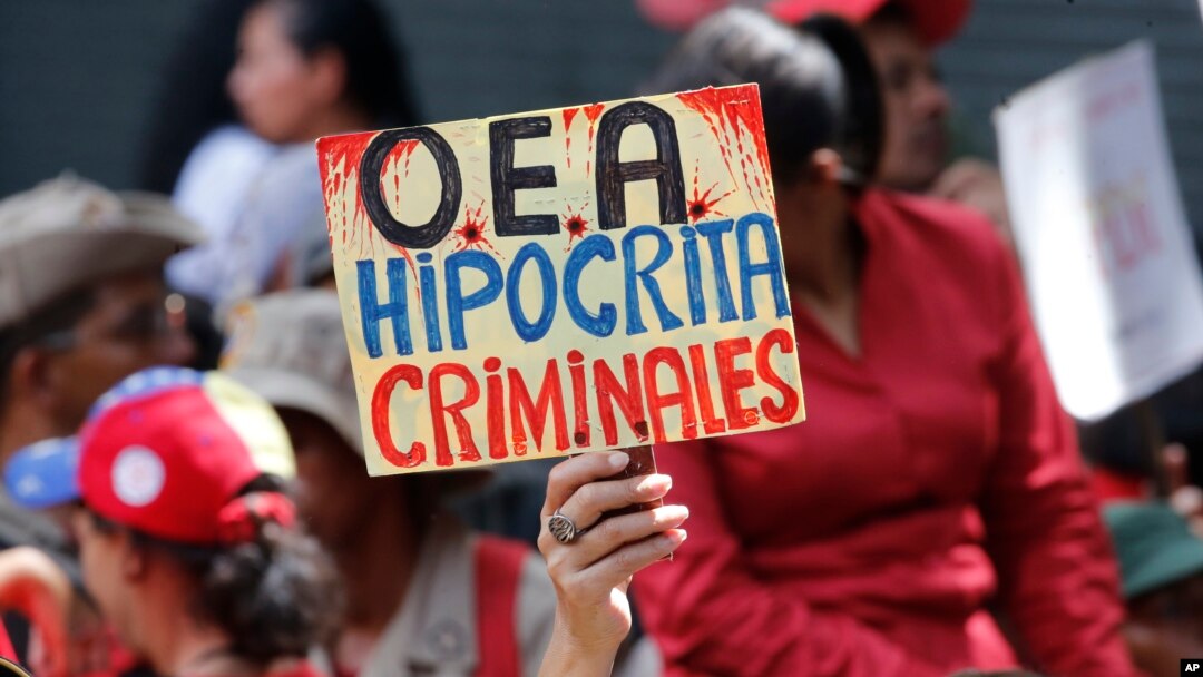 A supporter of Venezuela's president Nicolas Maduro, holds a sign that reads in Spanish "OAS Hypocrites, Criminals" during a government rally in Caracas, Venezuela,, April 27, 2019. 