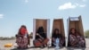 FILE - Women sit under UNHCR-branded cardboard boxes as they wait to be registered by authorities at the compound of the Agda Hotel, in Semera, Afar region, Ethiopia, Feb. 14, 2022. The Agda Hotel compound in Semera hosts hundreds of civilians who have fled violence.