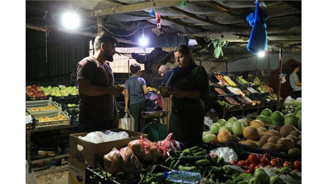 A displaced Iraqi woman from the minority Yazidi sect, who fled the Iraqi town of Sinjar, buys vegetables at the Khanki camp on the outskirts of Dohuk province, July 31, 2019.
