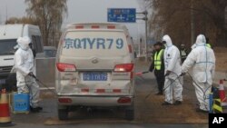 Workers disinfect passing vehicles in an area after the latest incident of African swine flu outbreak on the outskirts of Beijing, China, Friday, Nov. 23, 2018.