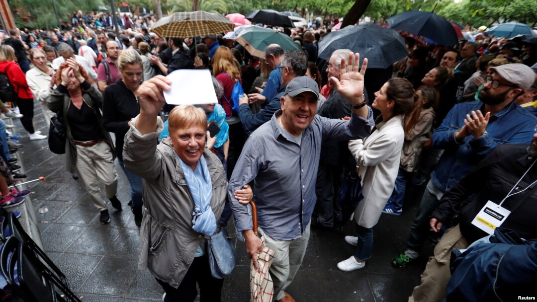 Voters are applauded as they leave a polling station for the banned independence referendum in Barcelona, Spain, Oct. 1, 2017. 