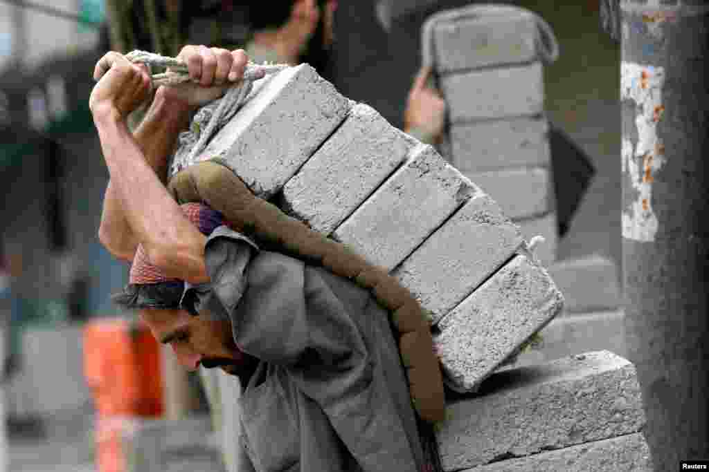 A laborer carries bricks on his back at a construction site in Karachi, Pakistan.