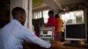FILE - A man uses a computer to read news at a cyber cafe after the Uganda Communication Commission restored the internet in Kampala, Uganda.