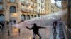 A demonstrator throws a stone as police use a water cannon during a protest against the newly formed government in Beirut, Lebanon January 22, 2020.