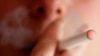 FILE - A woman smokes an e-cigarette, an electronic substitute in the form of a rod, slightly longer than a normal cigarette.