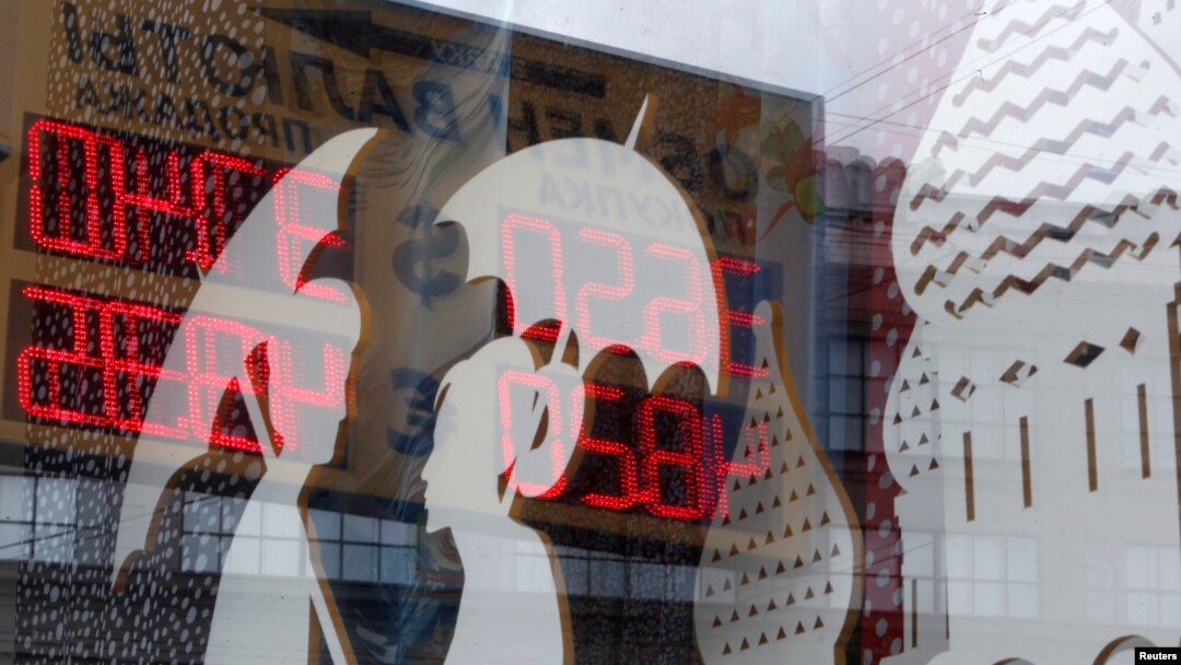 FILE - A board displaying currency exchange rates is reflected in a shop window in central Moscow, August 29, 2014.