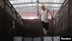 一名工人在河北唐山一家仓库里往卡车上装钢筋 (2015年路透社资料照)