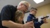 FILE - Instructor Jerry Kau shows student Joanna Zuber how to load a magazine into a handgun alongside Sam Minnifield during a Youth Handgun Safety Class at GAT Guns in East Dundee, Illinois, April 21, 2015.