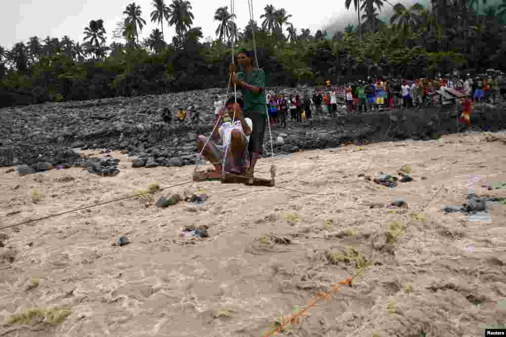 Residents use an improvised cable car to reach relief goods on the other side of rampaging river after a non-stop downpour flooded New Bataan town, Compostela province, southern Philippines, Jan. 14, 2014.