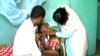 A boy suffering from side effects after receiving a measles vaccine, accompanied by his father, is checked by a nurse at Ebolowa regional hospital, in Ebolowa, Cameroon, Dec. 9, 2019. (Moki Edwin Kindzeka/VOA)