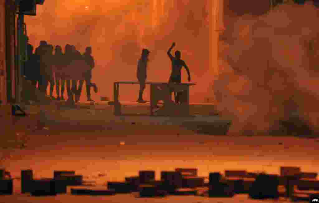 Tunisian protesters throw stones towards security forces in Tunis' Djebel Lahmer district after price hikes ignited protests in the North African country.