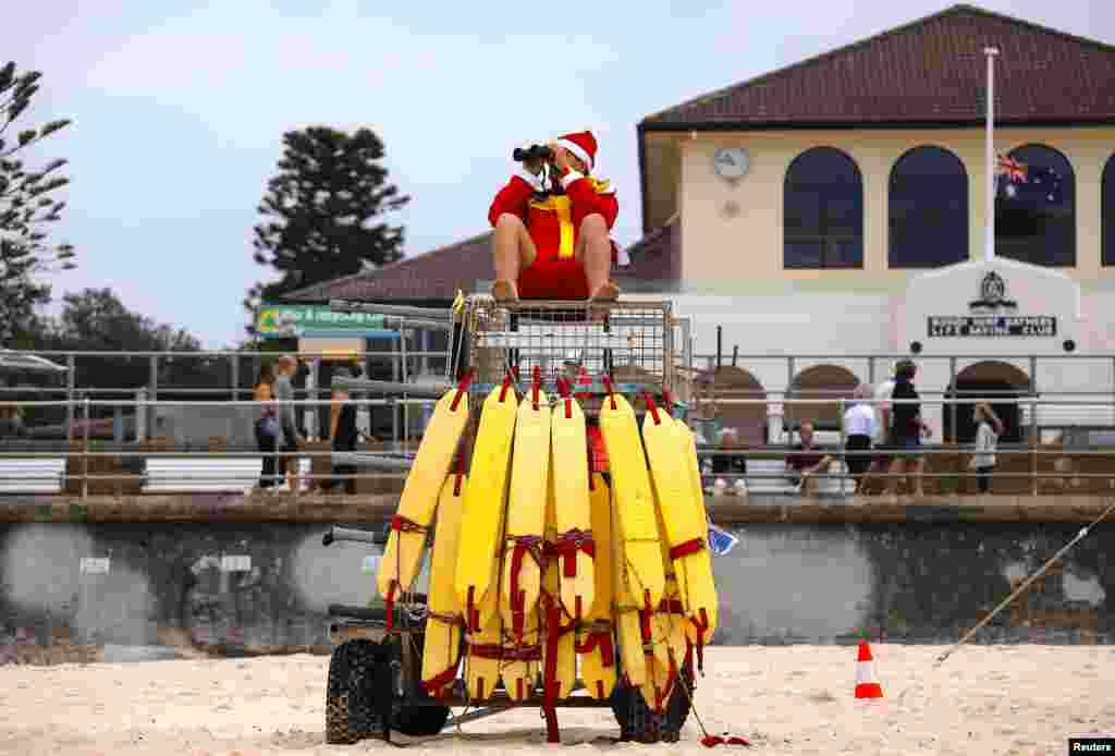 A surf lifesaver wearing a Christmas hat uses binoculors to watch swimmers on Christmas Day at Sydney's Bondi Beach in Australia.