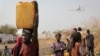 In this photo taken Wednesday, Feb. 26, 2014, a displaced South Sudanese woman carries a plastic jerry can with water in the United Nations camp that has become home to thousands of displaced people in Malakal, South Sudan. (AP Photo/Ilya Gridneff)