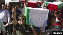 Palestinians carry flag-covered coffins containing the remains of Palestinian militants