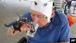 In this undated grab taken from video, a patient uses a robotic hand to drink from a cup, in Badalona, Spain. 