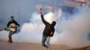 A demonstrator hurls a stone amidst smoke from tear gas fired by Indian policemen during a protest in Kashmir, in Srinagar, Jan. 13, 2018. 