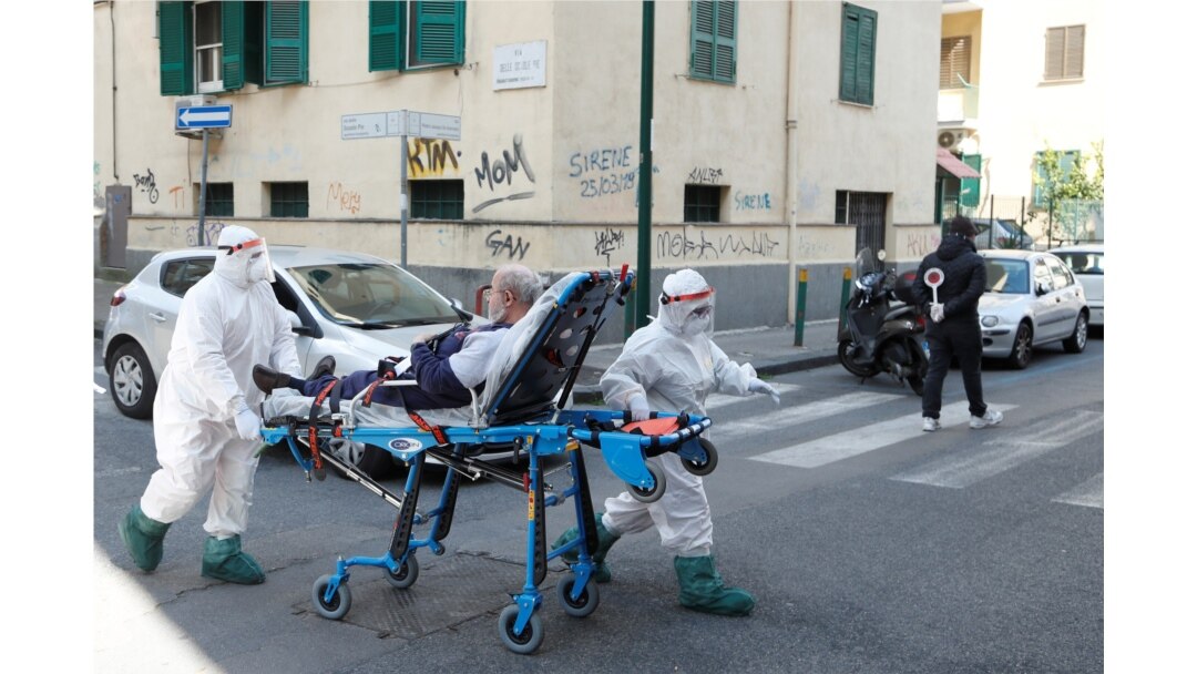 FILE - Medical staff in full protective gear move a patient on a stretcher down a street in Naples, as the spread of the coronavirus continues, Italy, April 2, 2020.