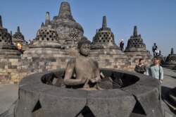 Tourists inspect a Buddha statue at Borobudur Temple in Magelang, Central Java, Indonesia, Aug. 12, 2019.