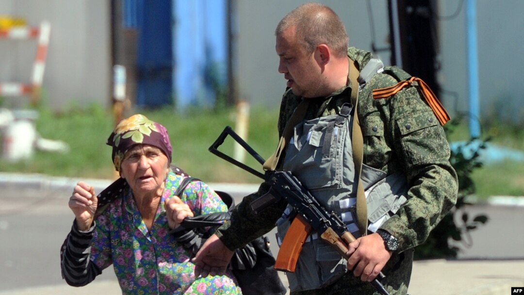 An armed pro-Russia separatist walks with a woman fleeing shelling near the train station in Donetsk, Ukraine, on July 21, 2014.