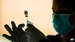 FILE - In this Sept. 14, 2021 file photo, a vaccine syringe is prepared in Reading, Pa. President Joe Biden has directed OSHA to write a rule requiring employers with at least 100 workers to force employees to get vaccinated or produce weekly test results.