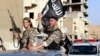 FILE - Fighters with the militant group Islamic State wave flags as they take part in a military parade along the streets of Raqqa province, northern Syria. 