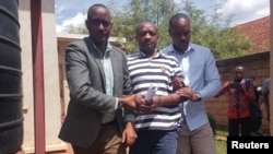 FDLR spokesperson, La Forge Fils Bazeye who was deported by the Democratic Republic of Congo to Rwanda is led away by Rwandan security members after appearing on charges of terror related accusations in a court Kigali, Rwanda, Apr. 8, 2019. 