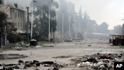 FILE - In this photo released by the Syrian official news agency SANA, damaged and blocked street where clashes erupted between the Syrian government forces and rebels, near the Abbassiyin square, east Damascus, Syria, March 20, 2017. 